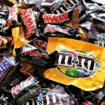 A bowl filled with various chocolate candies, including Twix, Snickers, and M&Ms, creating a vibrant dessert spread.