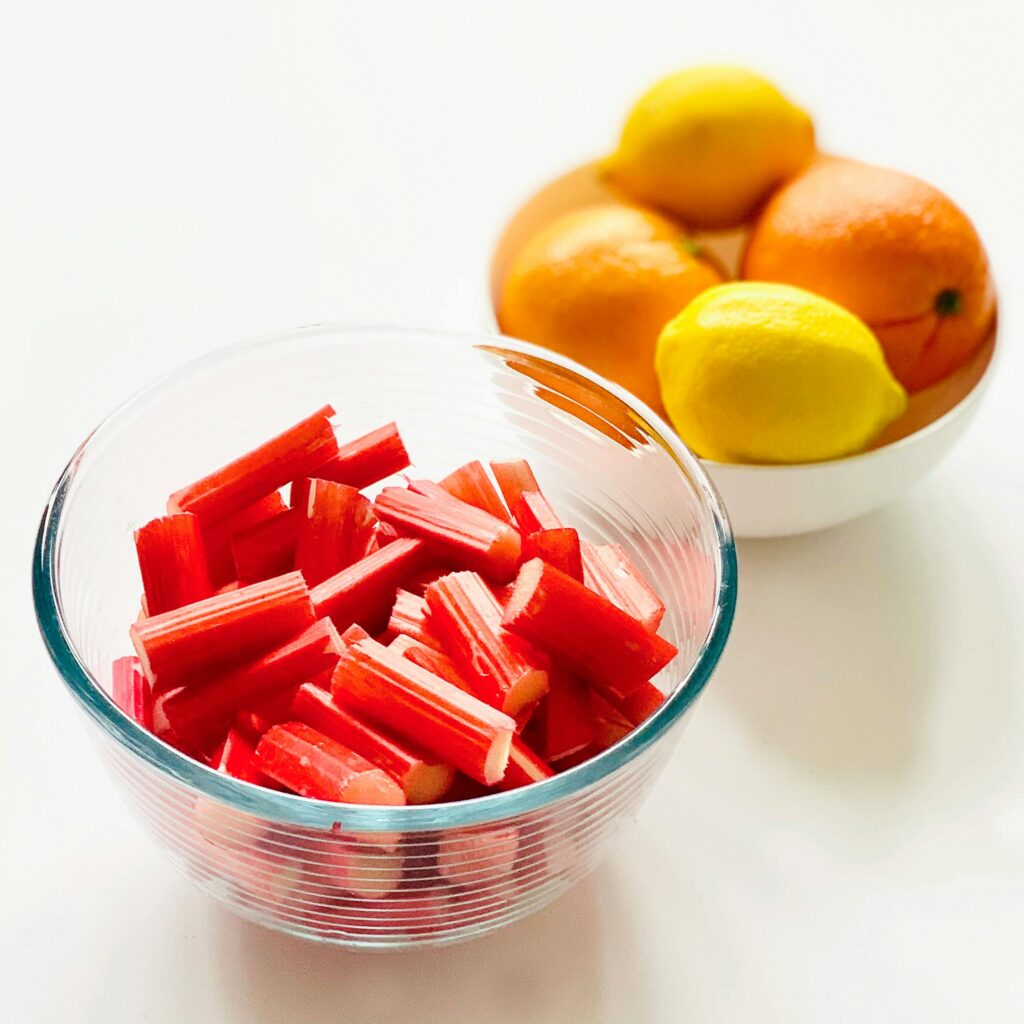 Bright and fresh rhubarb pieces with citrus fruits in bowls, offering a vibrant food display.