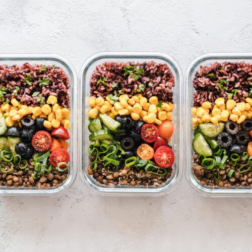Colorful healthy meal prep with corn, olives, tomatoes, and lentils in glass containers. Perfect for mindful eating.