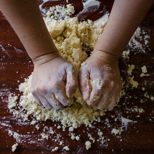 Close-up of hands kneading dough for baking on a wooden table, ideal for cooking themes.