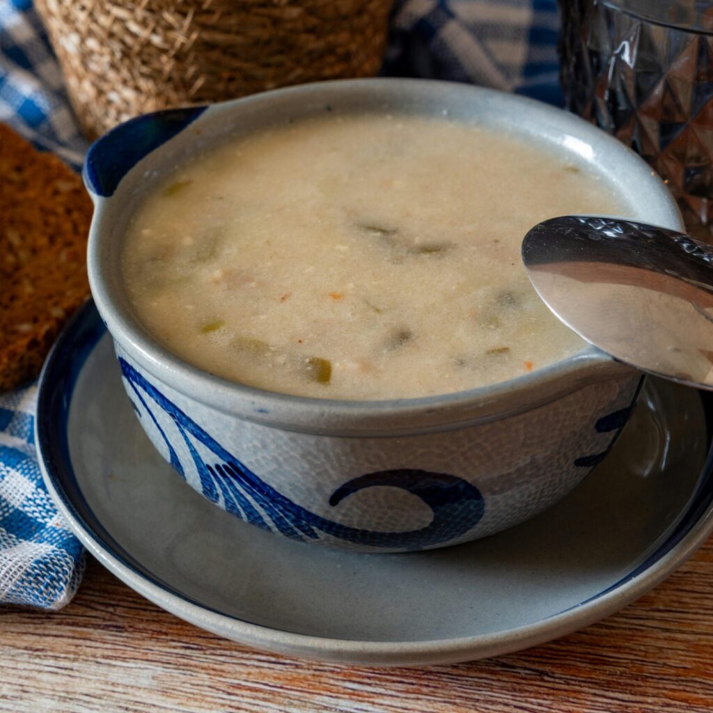 Warm soup in a stylish bowl with slices of wholegrain bread on a rustic table. Perfect for cozy dining.