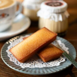 Close-up of a coffee and financier pastries on a wooden table, perfect for cozy cafe atmospheres.