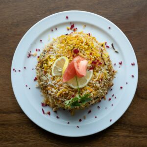 Top view of Indian biryani with lemon and tomato garnish on a plate, perfect for food photography.