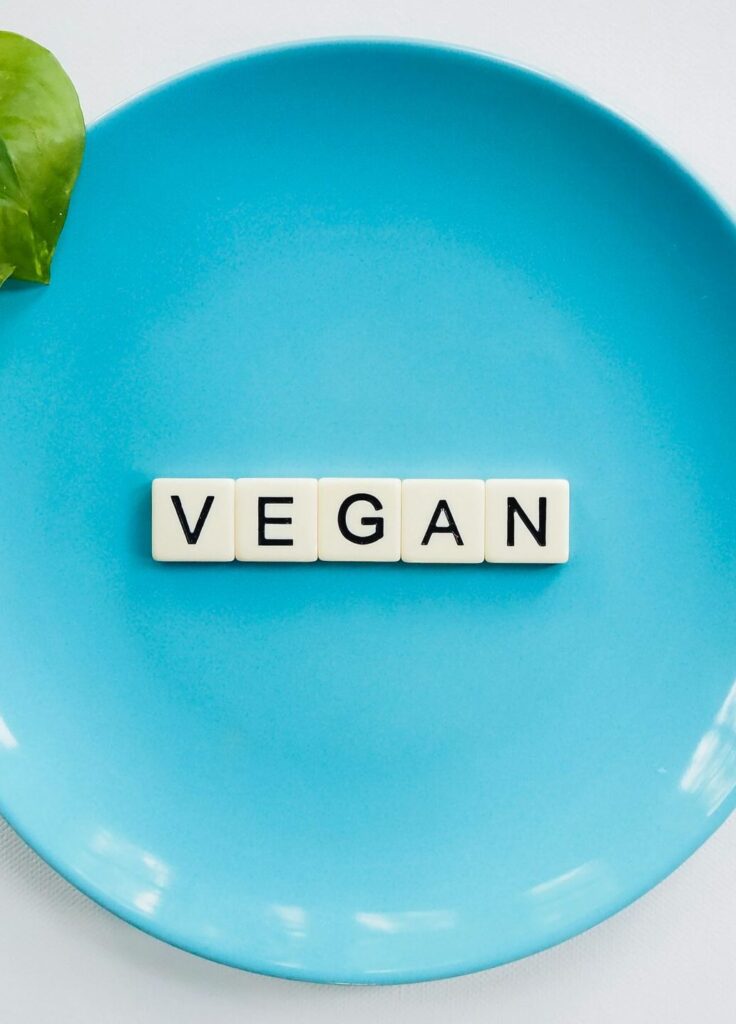 A blue plate with the word 'VEGAN' and a leafy plant, symbolizing a plant-based diet.