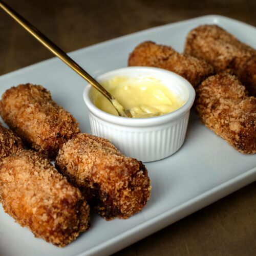 Golden-brown croquettes served with a creamy dipping sauce, perfect for a delicious meal.