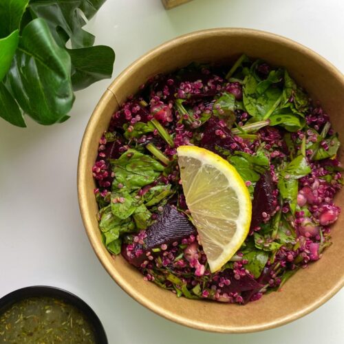 Vibrant beetroot salad with fresh greens and a lemon slice, perfect for a healthy meal.