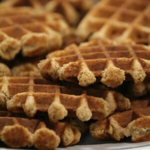 A stack of golden homemade waffles served on a white plate, ready to enjoy.